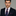 Man wearing a dark suit with a colorful floral tie and pocket square on a gray background
