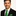 Man wearing a black suit with a green and red patterned tie and pocket square on a white background