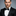 Man wearing a black tuxedo with a bow tie against a gray background