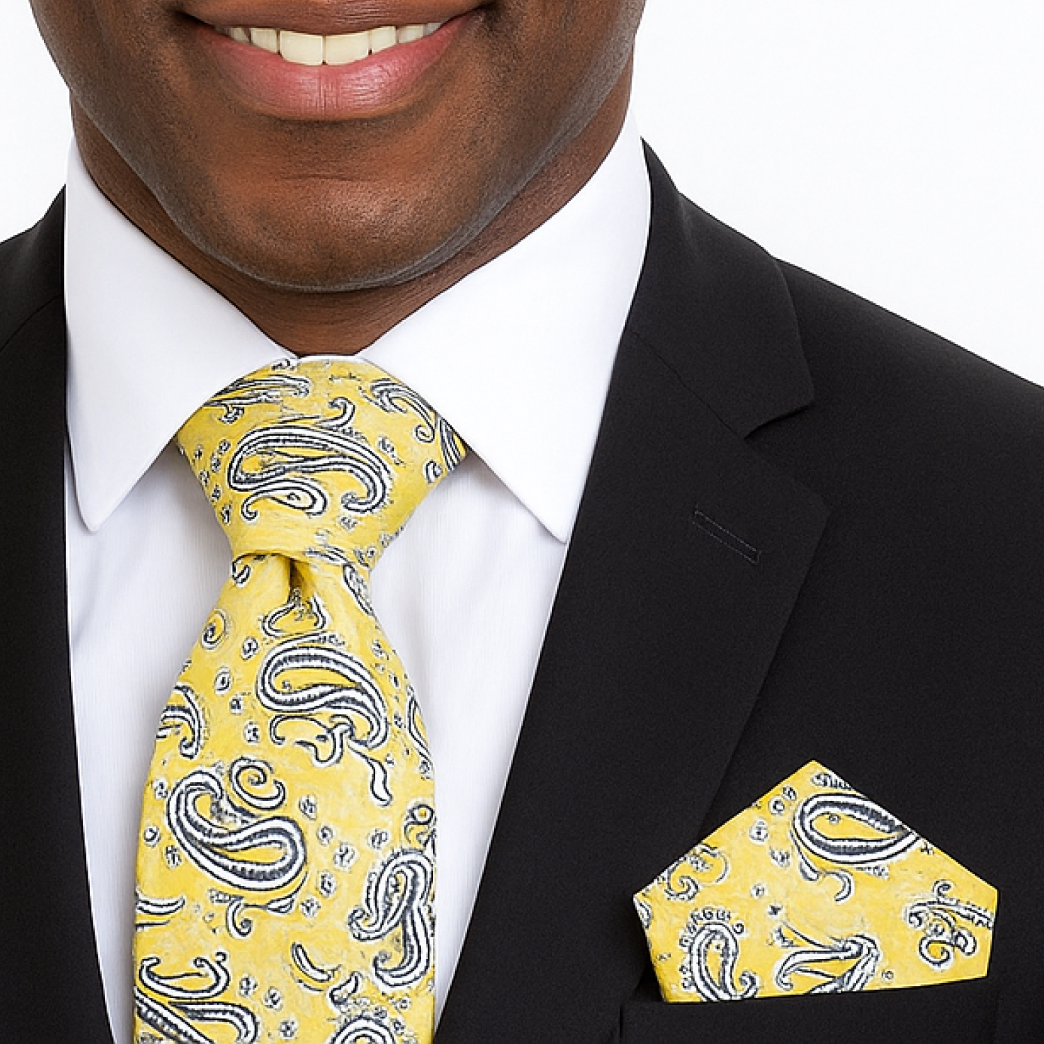 Man wearing a black suit with a yellow paisley tie and pocket square.