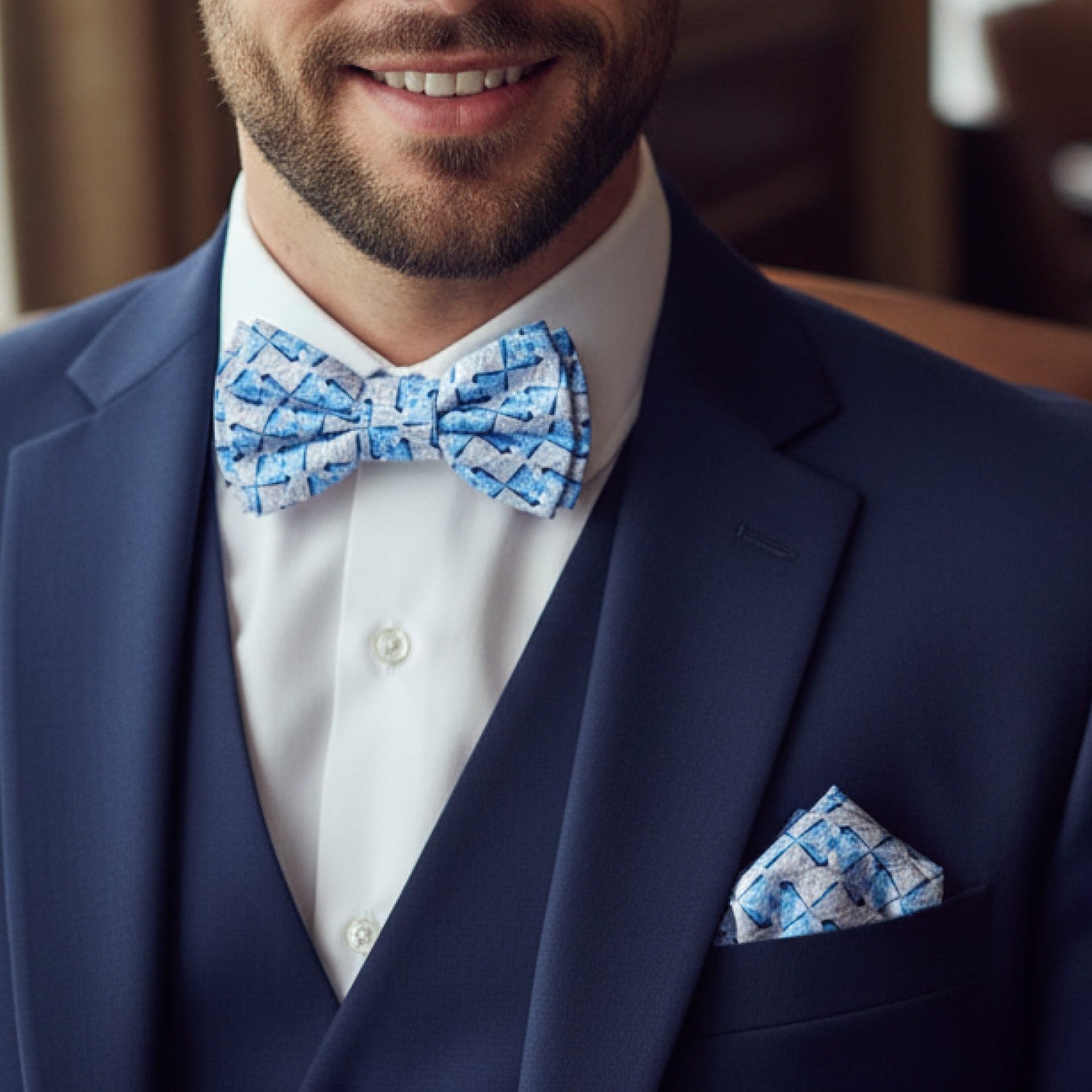 Man wearing a navy suit with a blue patterned bow tie and pocket square.