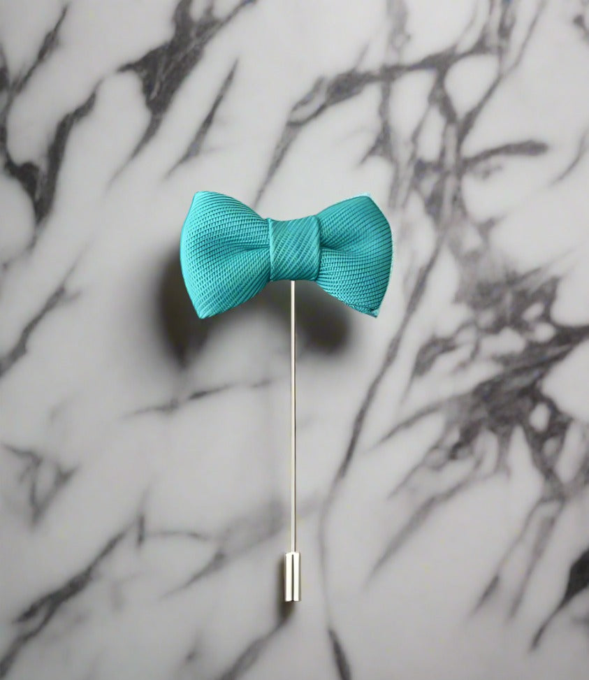 An Aqua Colored Bow Tie Shaped Lapel Pin||Aqua