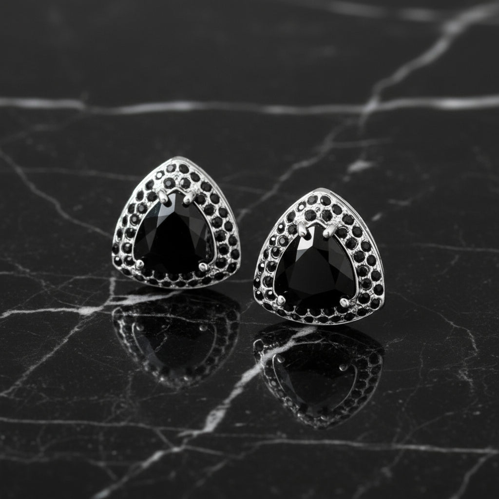 A set of diamond-shaped cuff-links with various colored stones set in silver metal, displayed on a marble surface.