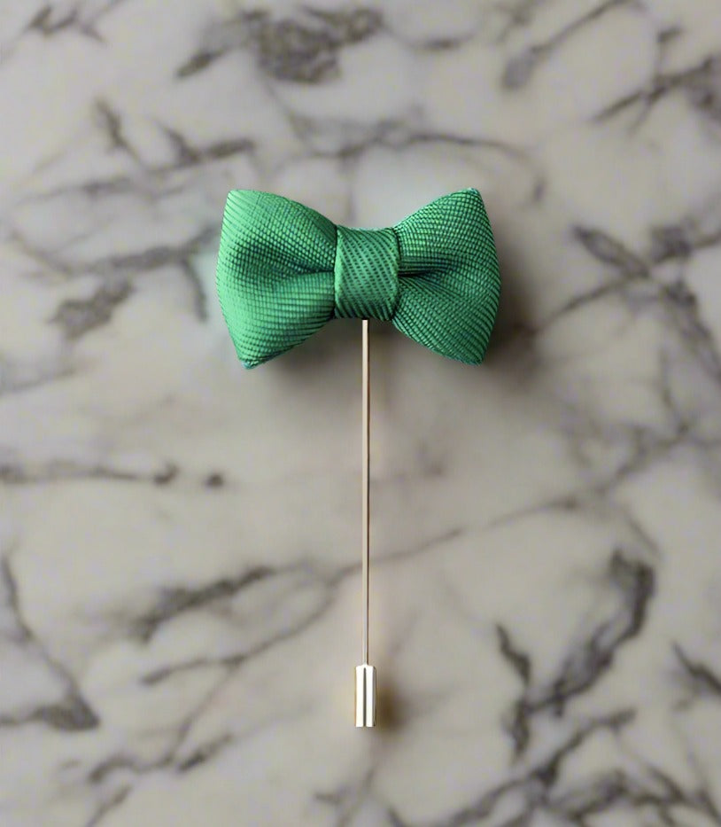A Green Colored Bow Tie Shaped Lapel Pin||Green