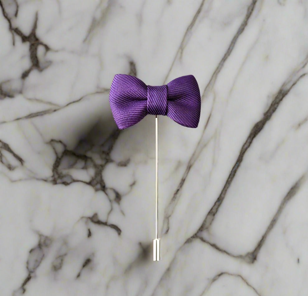 A Purple Colored Bow Tie Shaped Lapel Pin||Purple