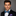 Man wearing a black suit with a colorful bow tie and pocket square on a gray background