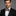 Man wearing a black suit with a colorful bow tie on a gray background