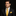 Man wearing a black suit with a yellow tie and pocket square on a dark background