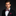 Man wearing a red and green bow tie with red square and black suit