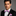 Man wearing a black suit with a colorful bow tie and pocket square on a gray background