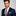 Man wearing a navy suit with a red and white patterned tie and pocket square on a gray background