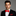 Man wearing a black suit with a red bow tie and pocket square on a gray background