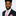 Man wearing a black suit with a pink tie and pocket square on a white background