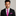 Man wearing a black suit with a pink patterned tie and pocket square on a gray background