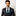 Man wearing a black suit with a blue tie and pocket square on a white background