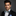 Man wearing a black suit with a colorful bow tie against a gray background