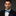 Man wearing a black suit with a colorful bow tie against a dark background