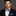 Man wearing a black suit with a colorful bow tie against a gray background