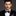Man wearing a black suit with a blue bow tie and pocket square on a dark background
