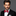 Man wearing a black suit with a red bow tie on a gray background
