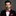 Man wearing a black suit with a red bow tie and matching pocket square on a gray background