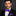 Man wearing a black suit with a colorful bow tie and pocket square on a dark background