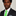 Man wearing a black suit with a green tie against a neutral background