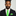 Man wearing a black suit with a green tie and pocket square on a gray background