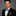 Man wearing a black suit with a colorful bow tie and pocket square on a gray background
