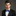 Man wearing a black suit with a blue bow tie and pocket square on a gray background