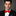 Man wearing a black suit with a red bow tie on a gray background
