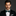 Man wearing a black tuxedo with a green polka dot bow tie on a dark background