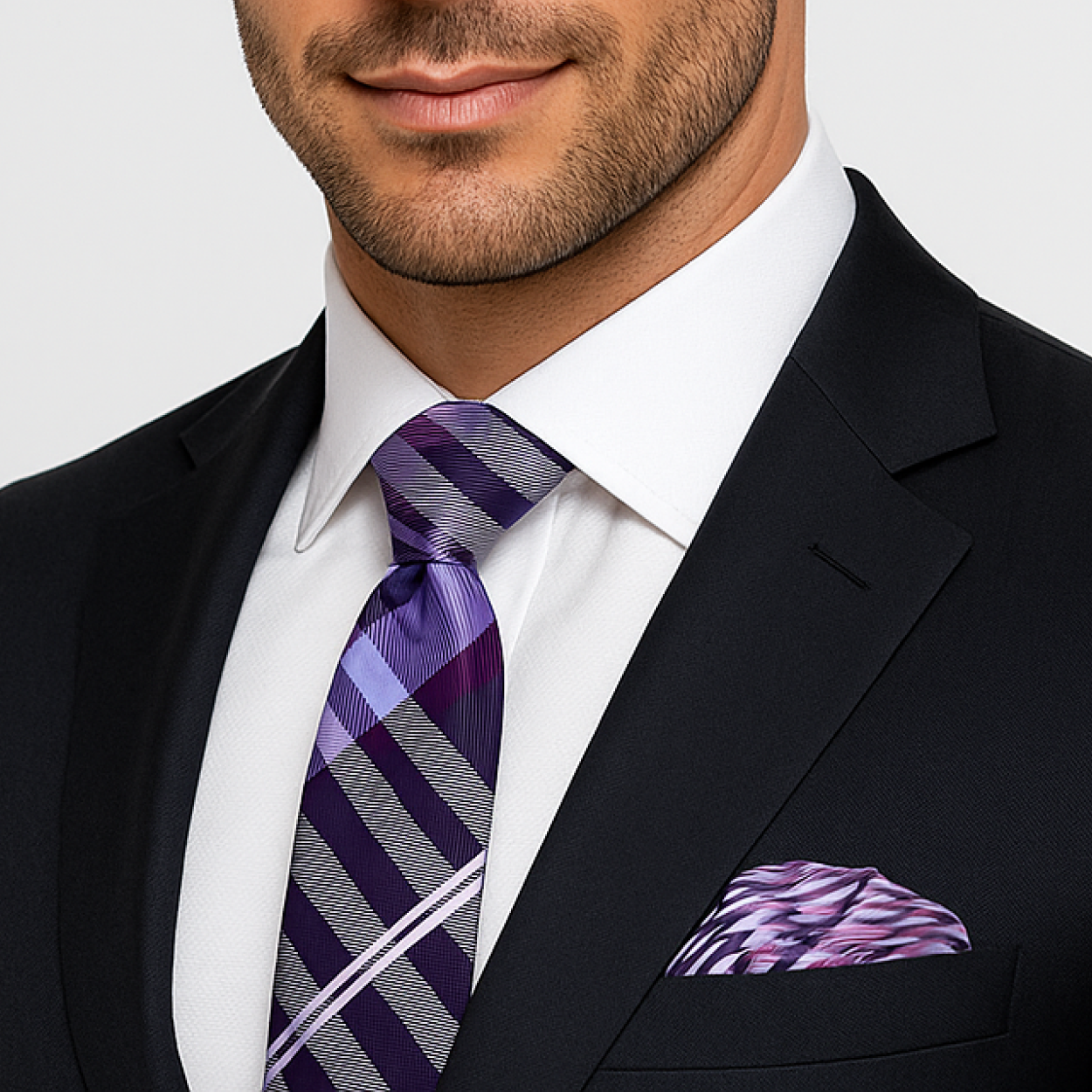 Man wearing a black suit with a purple plaid tie and matching pocket square.