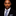 Man wearing a suit with a blue and silver checkered tie against a black background