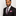 Man wearing a black suit with a patterned tie and pink pocket square on a light gray background