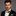 Man wearing a black suit with a gold bow tie against a gray background