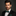 Man wearing a black suit with a green bow tie against a dark background