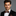 Man wearing a black suit with a brown bow tie against a gray background
