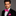 Man wearing a black suit with a pink bow tie and pocket square on a gray background