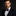 Man wearing a dark suit with a red polka dot bow tie and pocket square against a black background
