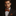 Man wearing a black suit with an orange polka dot bow tie and pocket square against a dark background