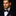 Man wearing a black suit with a blue bow tie featuring orange polka dots on a dark background