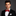 Man wearing a black tuxedo with a red bow tie on a gray background