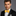 Man wearing a black tuxedo with a yellow bow tie on a gray background
