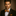 Man wearing a black suit with a orange bow tie and pocket square against a brown background