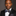 Man wearing a black suit with a colorful teal and red paisley bow tie and pocket square against a gray background