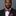 Man wearing a black suit with a colorful red and blue paisley bow tie and pocket square against a gray background