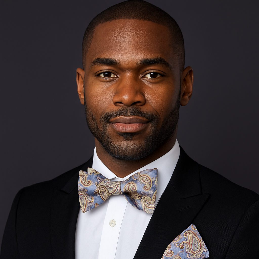 Man wearing a black suit with a blue paisley patterned bow tie and pocket square on a dark background