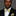 Man wearing a black suit with a yellow paisley bow tie and pocket square on a gray background