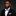 Man in a black suit with a purple and white stripe bow tie and pocket square on a dark background